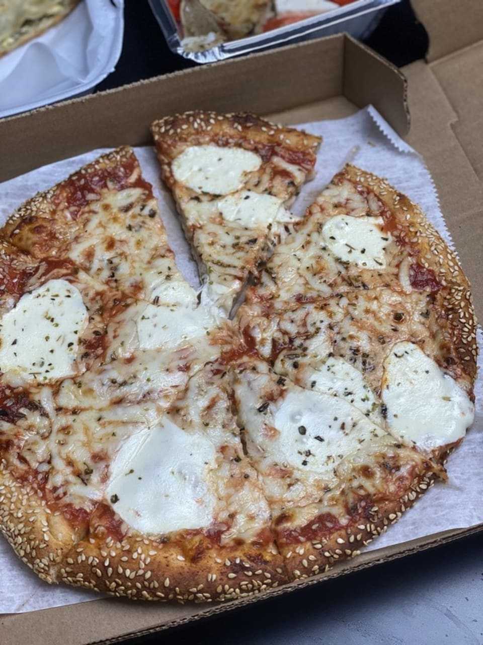 A cheese pizza from Stop Cafe Pizza & Grille with a curst seasoned with oregano and sesame seeds.
