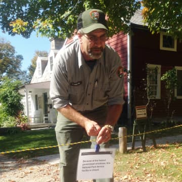Kevin Monthie, facility manager at Weir Farm National Historic Site, puts up the closed sign across the driveway in front of the visitor center. 