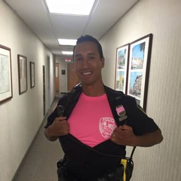 Ossining Police are selling a limited quantity of their pink department shirts, as displayed by Police Officer Addison Chavez. 