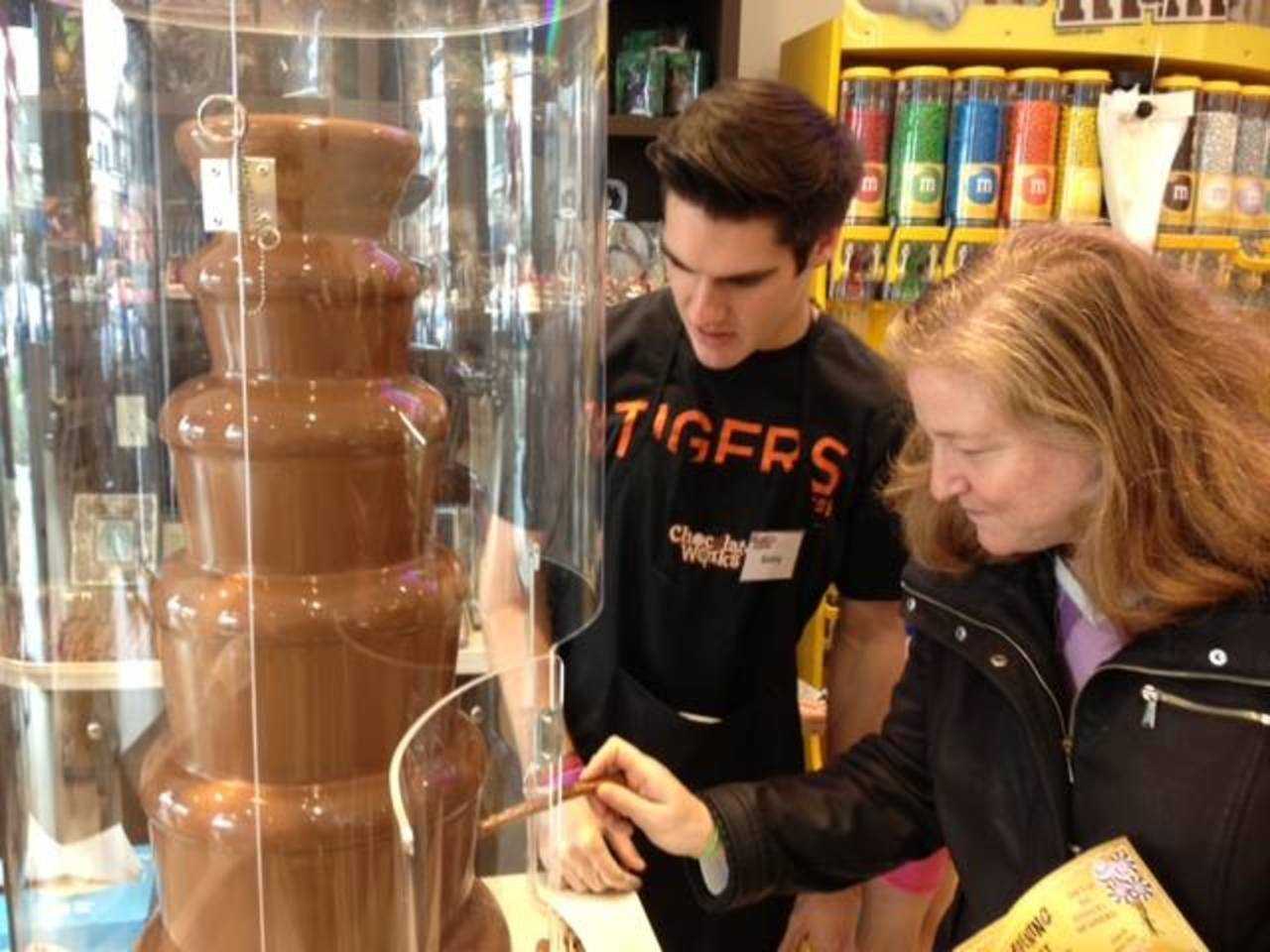 A Chocolate Works employee helps a customer get the most out of the chocolate fountain.