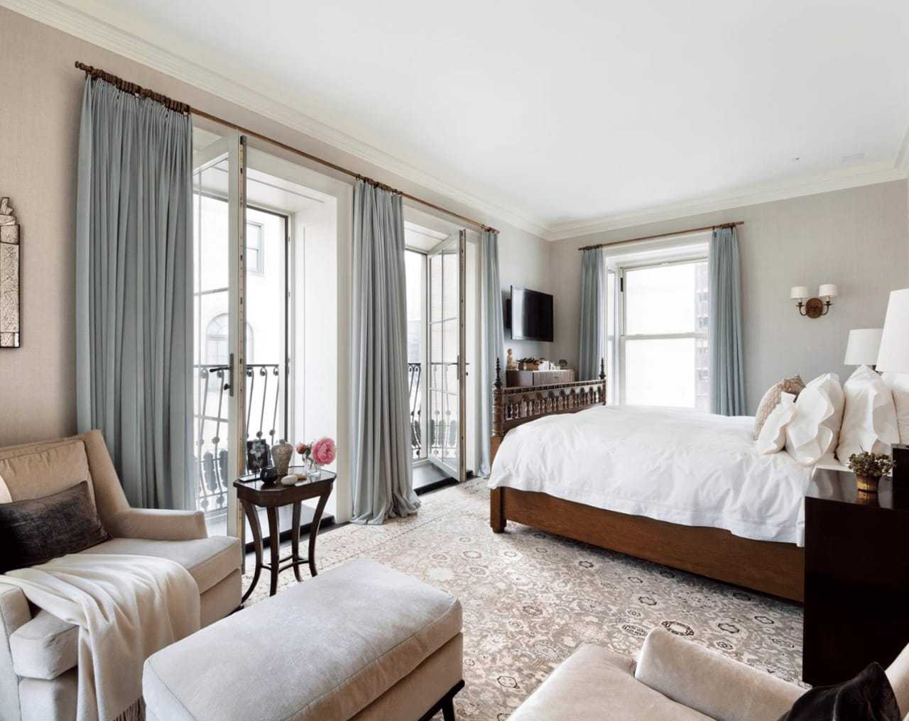 The bedroom features floor to ceiling windows that open onto a French balcony.