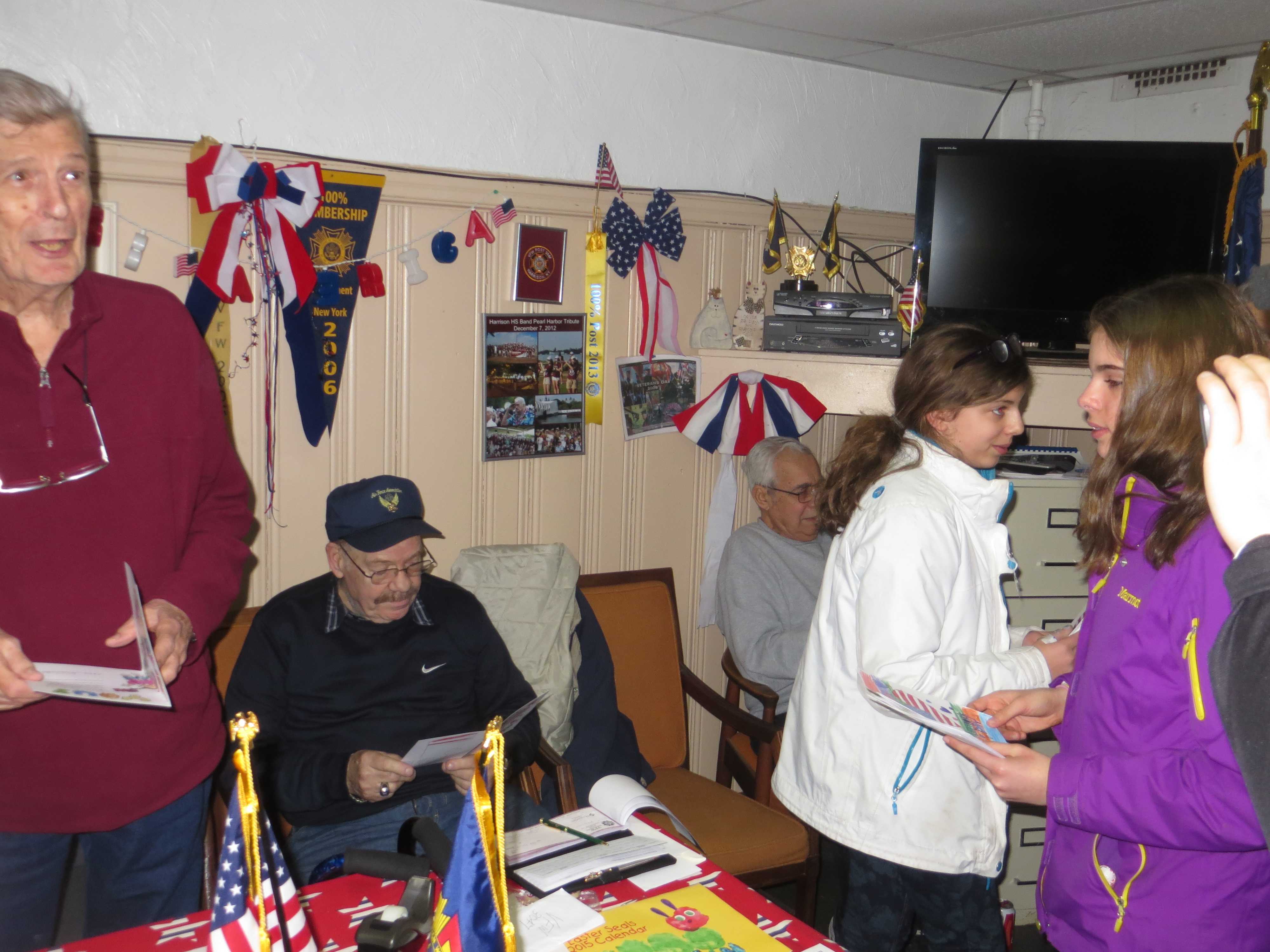 Harrison VFW Commander Fred Neale, left, and other veterans look at Valentine's cards distributed by Armonk students.