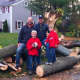 Brad Beck, left, his friend John Harrison, and Harrison's two sons Christopher and Jack, stand with the tree eight men on Brooks Road cut up to clear traffic on the street. 