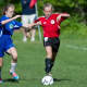 New Canaan's Lucy Coutts controls the ball under pressure from a Darien player.