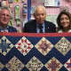 Norwalk Mayor Harry Rilling, left, and his wife, Lucia, right, present a quilt at Christie's Quilting Boutique in Norwalk on Saturday.