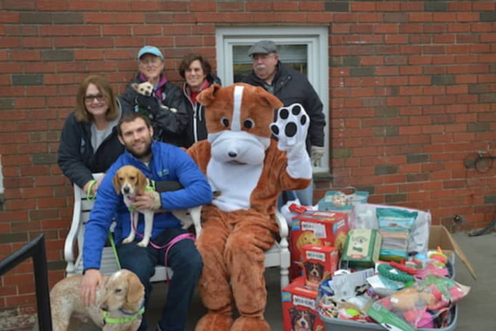 Paws and Play’s owner Matt Sellechia, mascot Pawley (Andy MacMillan) and members of the Paws and Play organization with treats, toys and food it donated to Pet Rescue.