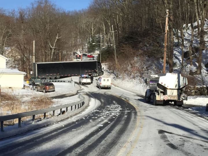 Slippery roads caused a large tractor-trailer to become stuck when it couldn&#x27;t travel up a grade in the roadway.