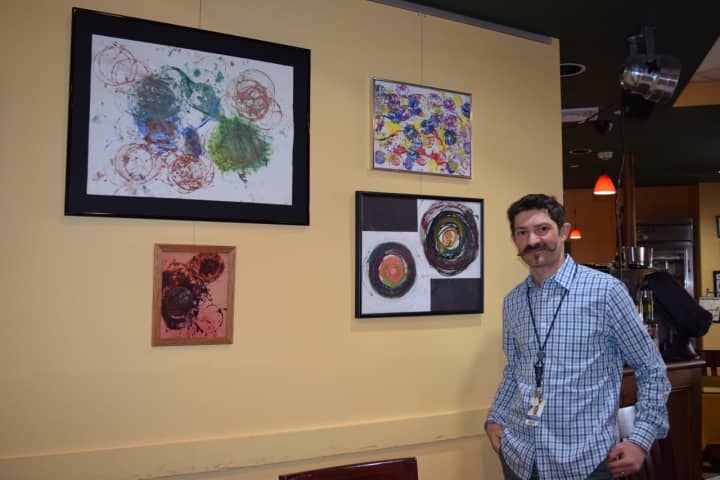 Jesse Steiner in front of artwork made by students on the autism spectrum.