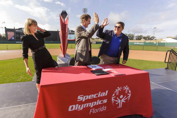 Joe Dzaluk, center, after signing the contract naming Orlando as host of the 2022 Special Olympics USA Games. He celebrates with Marc Edenzon, managing director of Special Olympics N.A.  &amp; Sherry Wheelock, president/CEO of Special Olympics Florida.