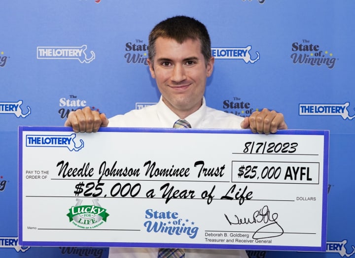 Steven Twomey, a trustee for Needle Johnson Nominee Trust, poses with a Lucky for Life check that guarantees the holder of the trust $25,000 a year for life.