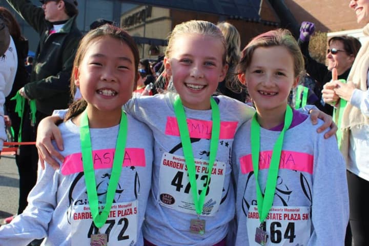 Young runners pose with their medals after finishing the Girls on the Run 5K at the Garden State Plaza.