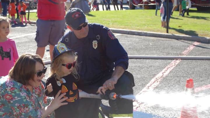 Chrissy LaBate and her daughter Veronica learn how to spray a fire hose at the Ho-Ho-Kus Fire Department open house.