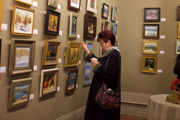 A shopper looks at small paintings at the Ridgewood Art Institute&#x27;s latest show.