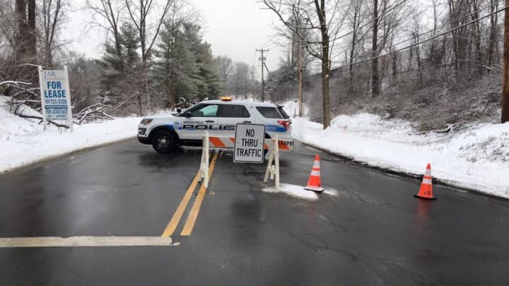 A police car blocks Vale Road in Brookfield as repairs are made on a damaged utility pole.