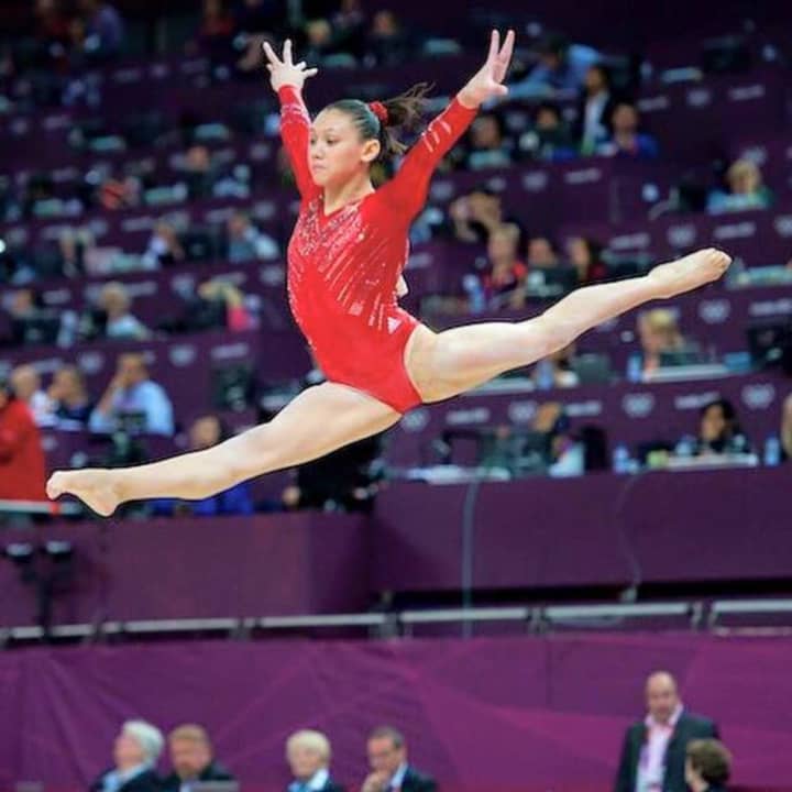 A Paragon gymnast leaps across the beam.
