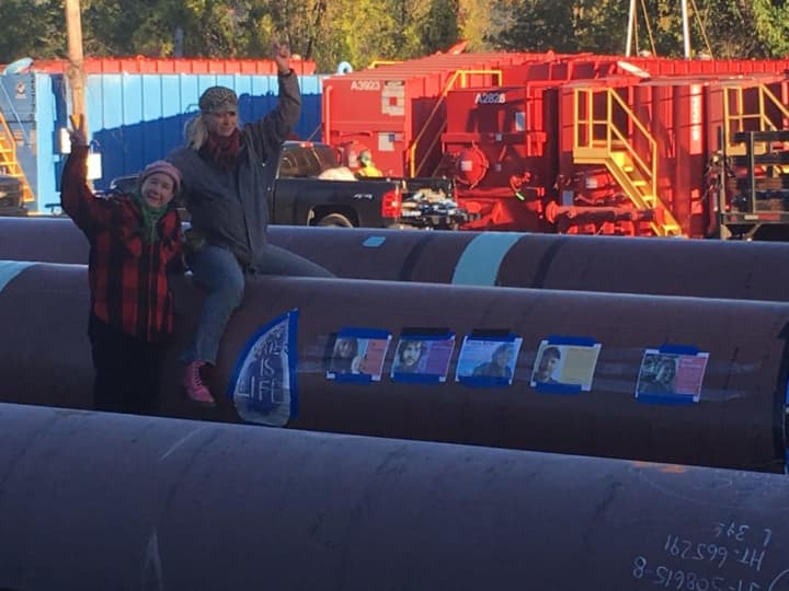 Two protestors sit atop one of the pipes Monday being used to construct the Algonquin Pipeline project.