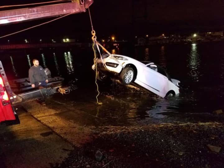The car is pulled from the Saugatuck River early Sunday in Westport. An elderly man died after the car went into the chilly waters Saturday evening, but first responders saved a woman.