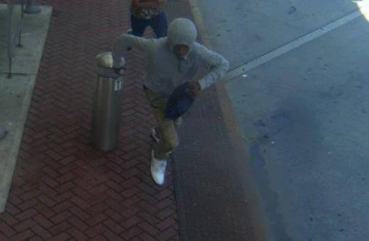 A suspect in a gray-hooded sweatshirt runs with the purse after snatching it at the Pulse Point bus station in Norwalk.