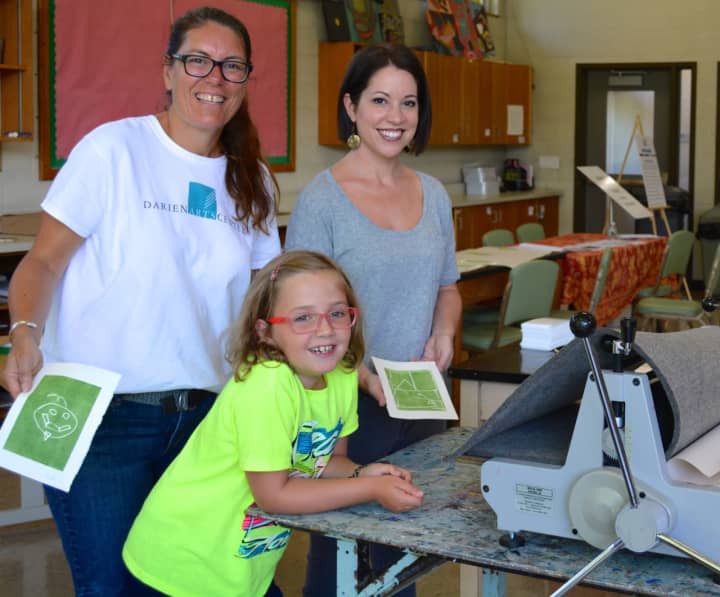 DAC Visual Arts Director Beth Cherico and instructor Jill Sarver help Anora Voss with a printmaking project.