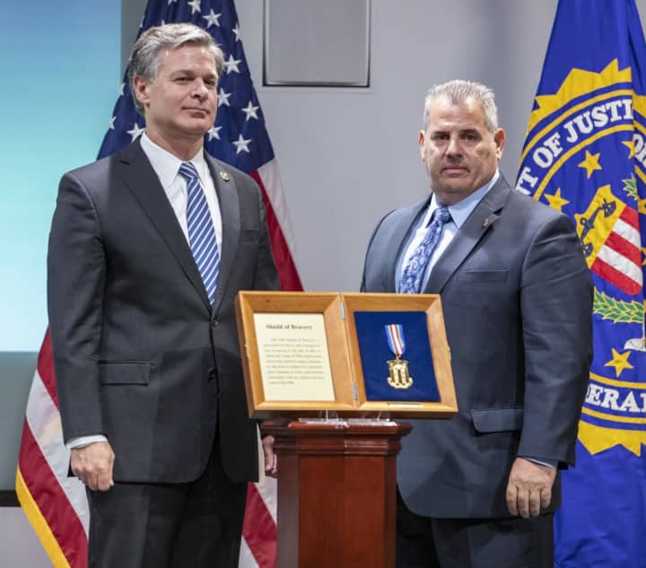 FBI Director Christopher Wray, left, presents Shield of Bravery to Detective Terence Malone