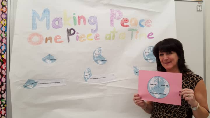 Esther Fletcher with a poster her students made for the &quot;Peace By Piece&quot; project.