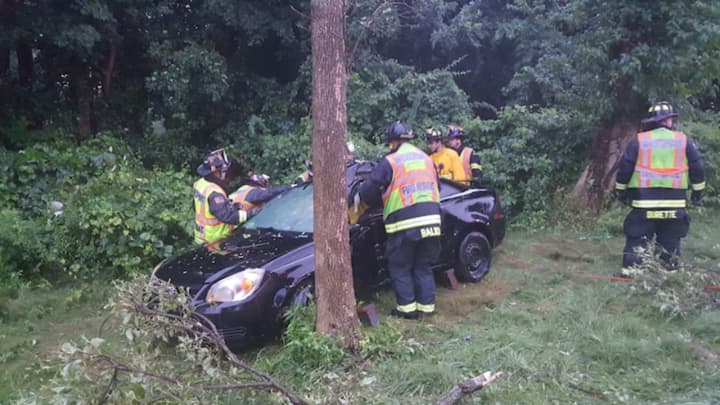 Westport firefighters respond to a crash scene after a car went down an embankment on the Merritt Parkway during heavy rains on Saturday morning.