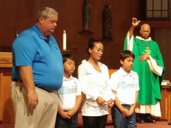 Richard and Jung Courville, with their children, receive a blessing at St. Jerome in Norwalk.