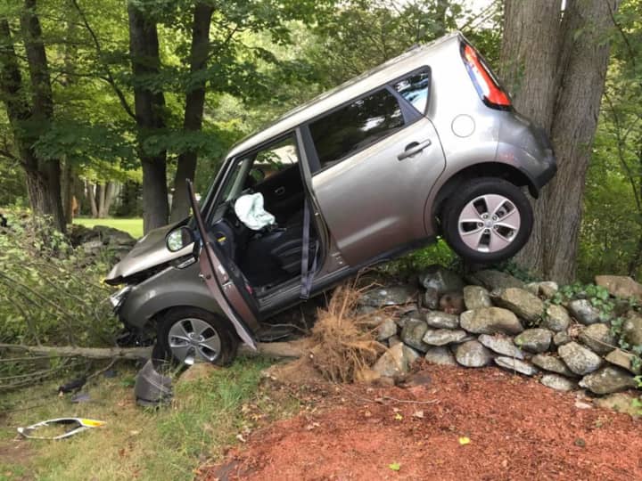 An SUV ends up balanced on a stone wall after a crash on Thompson Street in Shelton on Thursday.