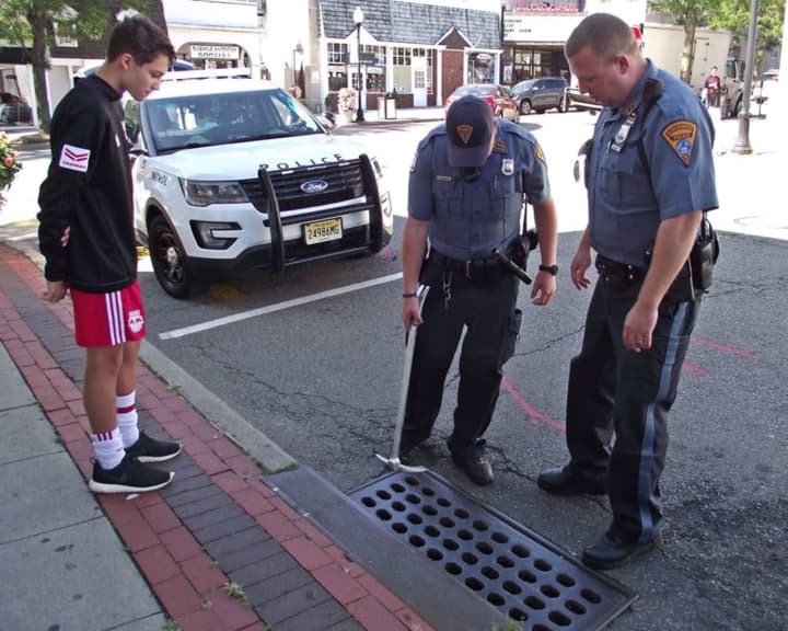 Police rescue a cell phone from a storm drain in Ridgewood.