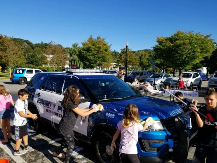 Students from Mount Kisco Elementary School wash local police cars during a school fundraiser.