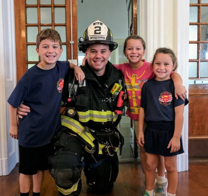 Hackensack Leitenant Mike Oates with his children, who attend the Fairmount School. Firefighters on Monday visited Fairmount, where they made a presentation and let the students try on their bunker gear.
