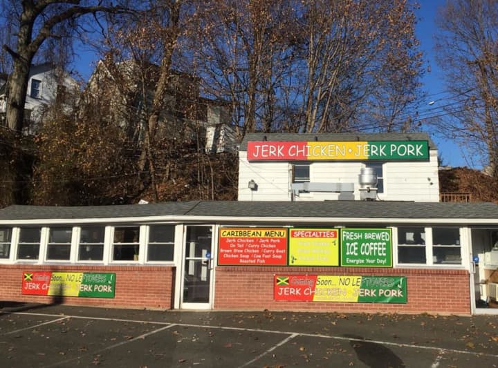 Brightly colored signs for a new eatery — Jerk Chicken and Pork — fill the facade of the former Swanky Franks in Norwalk.