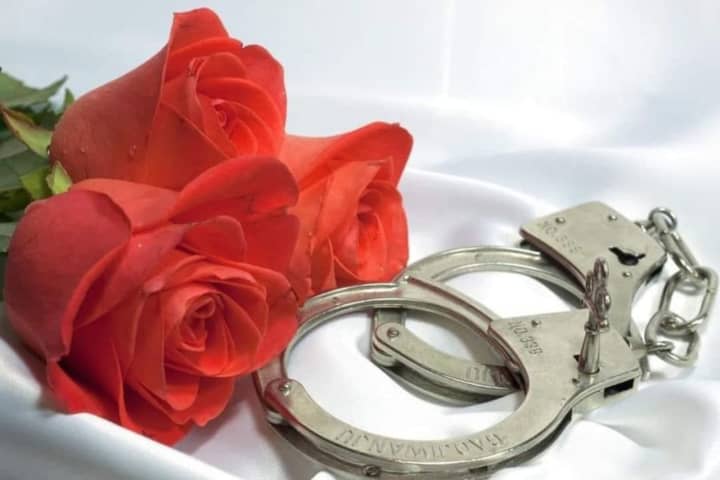 Roses an handcuffs on a satin sheet.