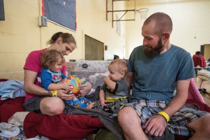 Two parents play with their children, ages 2 and 1, on their cot in a shelter in San Antonio on Sunday as Hurricane Harvey slams Texas.
