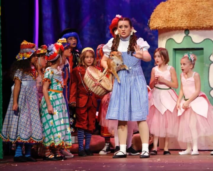 Dorothy (Kate Murphy) and munchkins from the cast of New Canaan High School&#x27;s production of &quot;The Wizard of Oz.&quot;