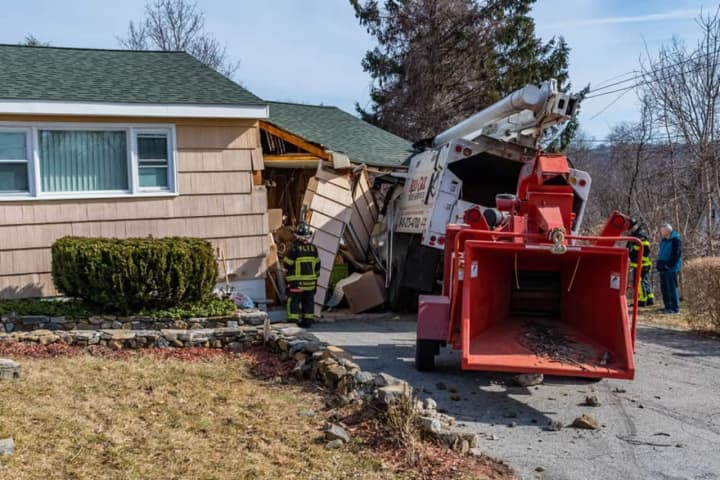 A truck rolled into a house while working on trees in the area.