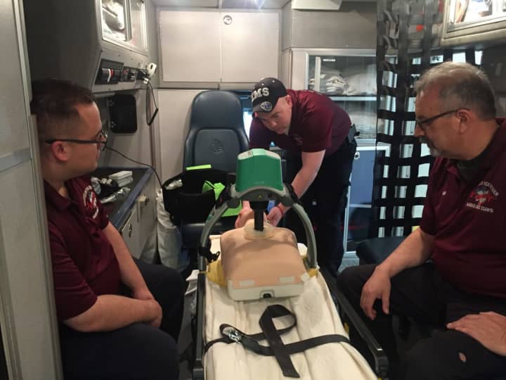 From L: EMT Rich Sassi, QAQI Coordinator Jeff Ashdown and Allan Simmons demonstrate the corps&#x27; new Lucas Device, which provides mechanical compression.