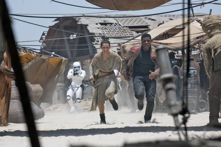 Rey (Daisy Ridley) and Finn (John Boyega) take fire from stormtroopers in a scene from “Star Wars: The Force Awakens.”