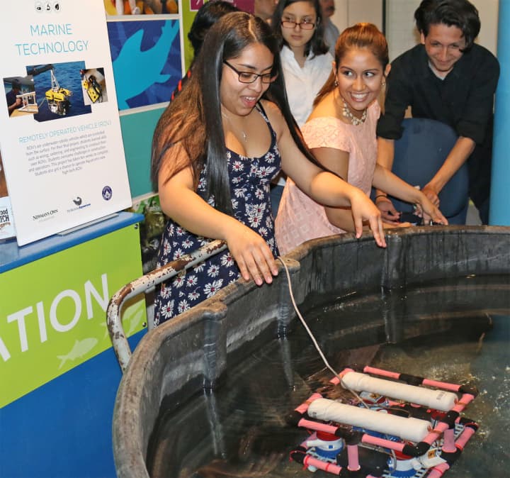 Mary Guerra, left, places her team’s remotely operated vehicle (ROV) in the water for demonstration during the May 23 end-of- year celebration for Norwalk teens participating in the TeMPEST after-school program at The Maritime Aquarium at Norwalk.