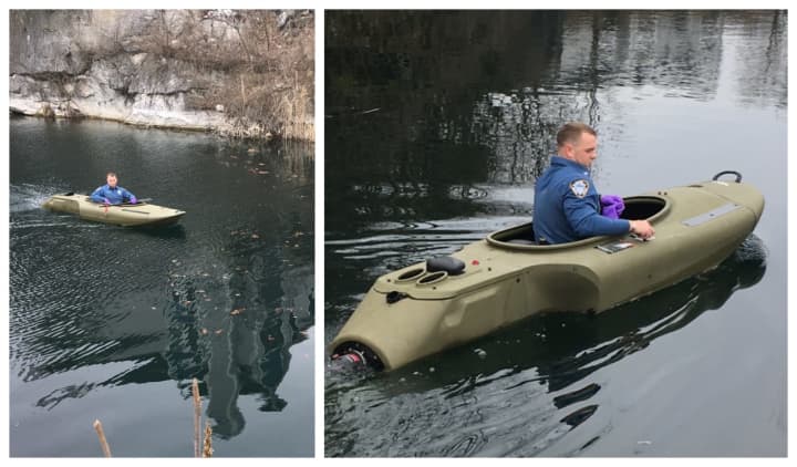 Police use a special motorized kayak to recover the body of a dog who leapt into a Hamburg quarry Tuesday.