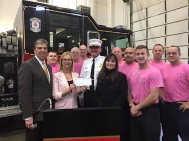 Dr. Donna Twist, executive director of Norma Pfriem Breast Center, holding the check tor $6,363 donated by Bridgeport Firefighters. Bridgeport Fire Chief Richard Thode, in white, is on the right.