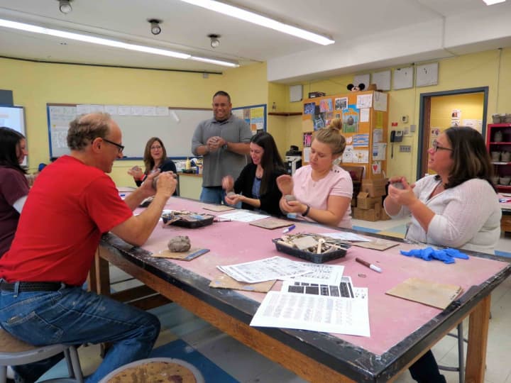 Teachers at Todd Elementary School in Briarcliff Manor make Native American-inspired clay pots with the help of artist-in-residence Cliff Mendelson, left; and art teacher Paul Villanueva, standing.