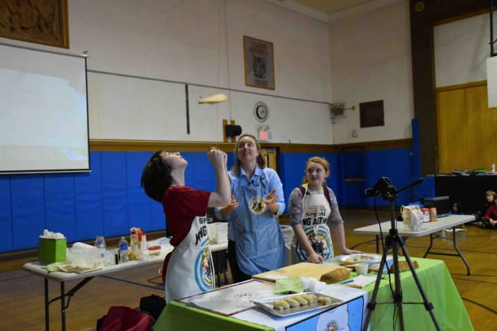 Amy Driscoll of the Vermont-based King Arthur Flour Co. shows seventh-graders at the Pierre Van Cortlandt Middle School in Croton-on-Hudson how to toss pizza dough. Doing the tossing is student Charlie Azalone . At right is student Desiree Cilentl.