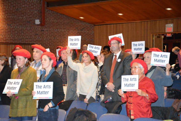 Opponents of a proposed cut in arts funding for the 2016 Westchester County budget attend a hearing with red berets and signs.