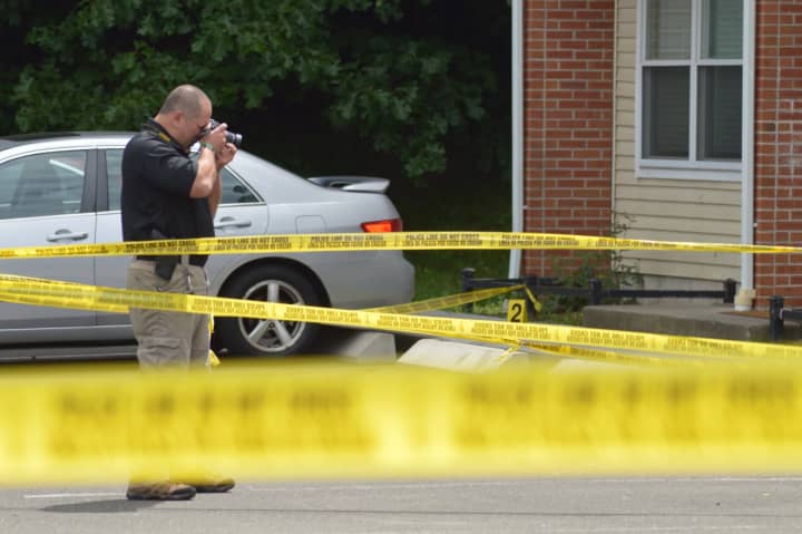 A Norwalk police officer takes a photo at the scene of a stabbing in Norwalk Wednesday morning.