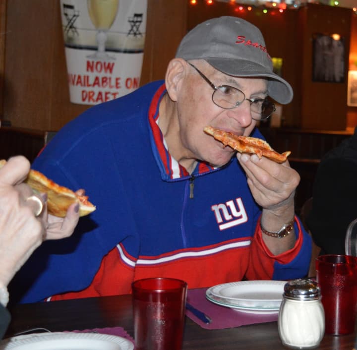 A member of The Spartans bites into a slice of cheese pizza at Patsy&#x27;s Tavern and Restaurant in Paterson.