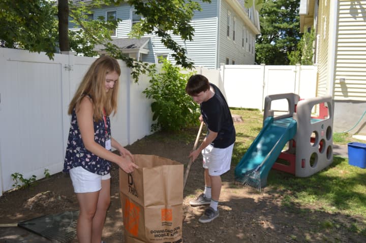Jessica Power, of Torrington, and Nick Loris, of Fairfield, help clean the backyard at Caroline House in Bridgeport, as part of The SHU Journey summer program.
