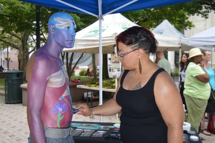 Alicia Cobb, of Stratford, demonstrates her body painting technique at the downtown farmers market in Bridgeport.