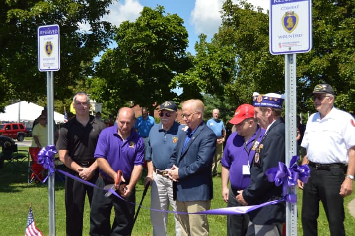 The ribbon-cutting is performed by Dan Hayes, Lee Teicholz, John Kwiatkowski, Lt. Col. Michael Zacchea, and Mayor Mark Boughton, marking the official Purple Heart parking spots at the War Memorial in Danbury.