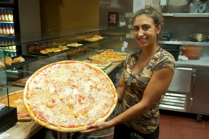 Shelby Squillante of Amalfi Pizzeria holds one of the restaurant&#x27;s massive, 24-inch pies.